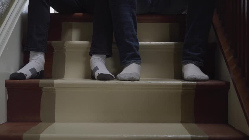 Two people in their socks sit on the stairs