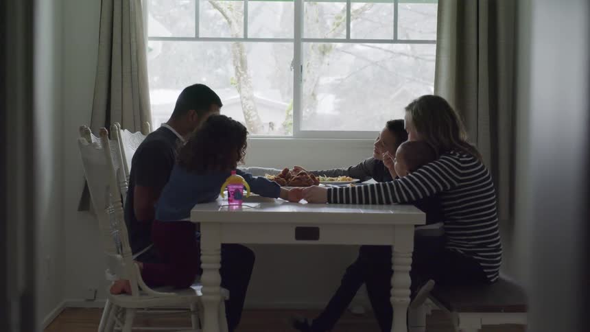 A family sits at the dinner table and prays together before eating