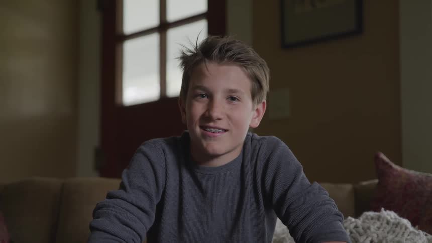 A child smiles while sitting in a room