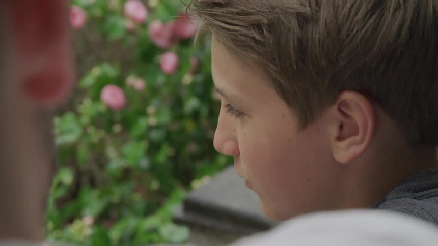 A young boy sits on a front step with another person