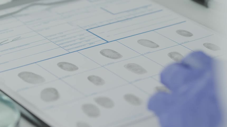 A technician studies a fingerprint card