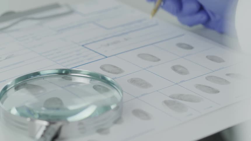A person makes notes on a piece of paper with finger prints on it