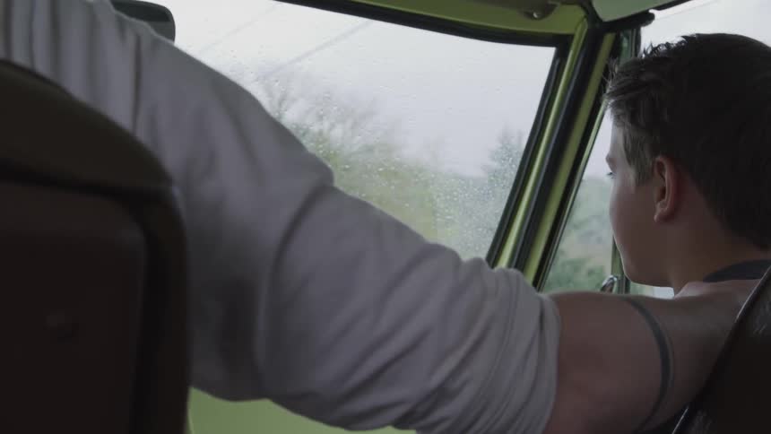 Son looking over and smiling at his dad while riding in a car