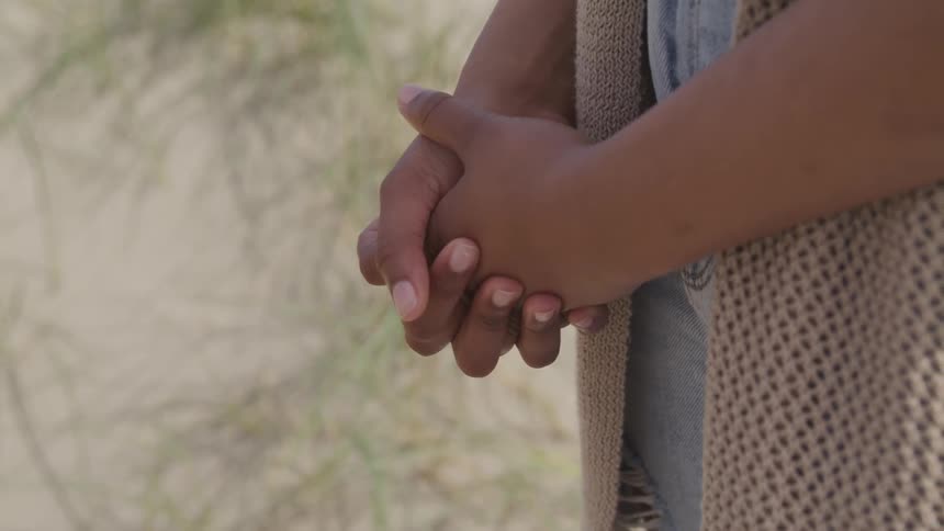 A woman is holding her hands together outdoors