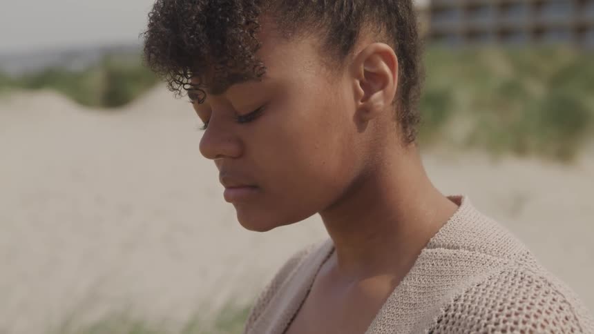 A woman closes her eyes on the beach