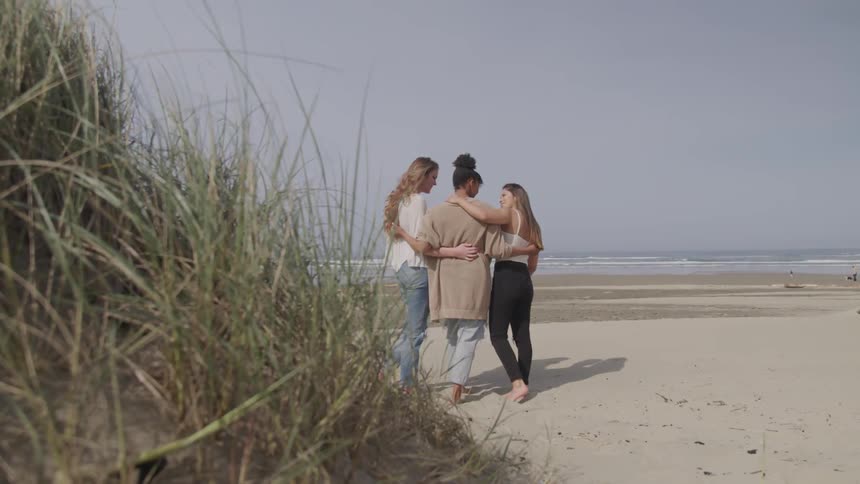 Three women stand on the beach