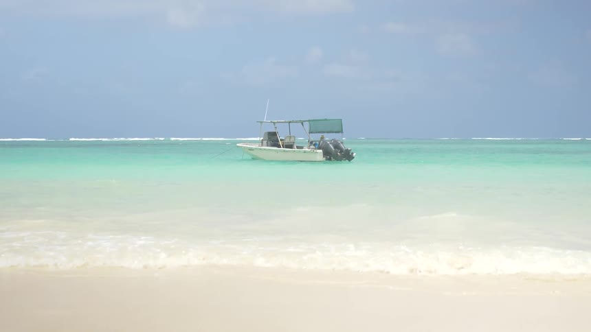 A ship with 2 motors is floating in the waves near a beach