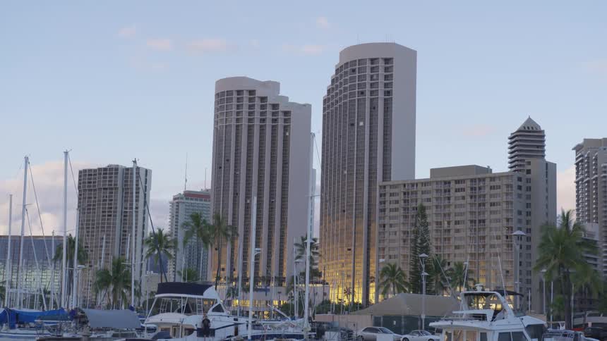 Vehicles and boats parked along the front of large buildings
