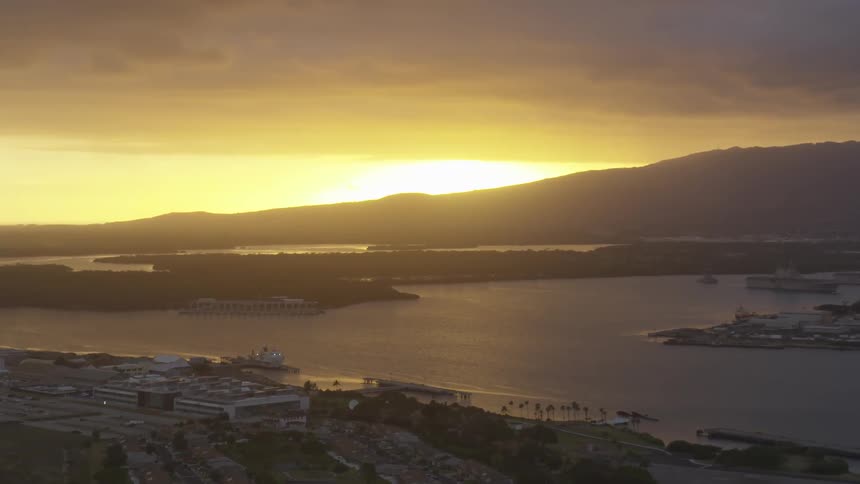 The sun rising over a coastal town with mountains