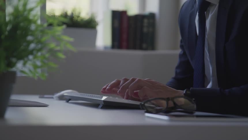 A man is typing on a computer while sitting in an office