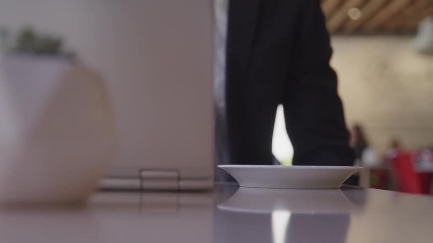 A person picking up a teacup and putting it down than typing on a laptop