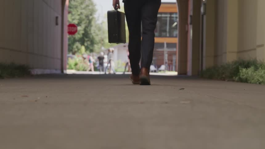 Man in business suit walks down alley toward street
