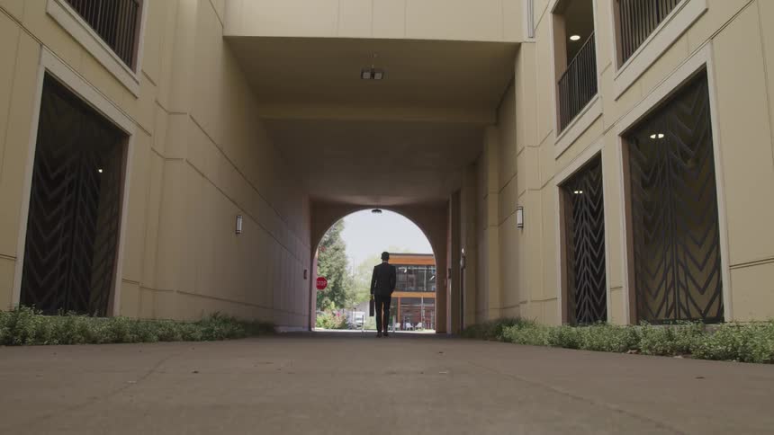 A young man carrying a briefcase walks through a corridor