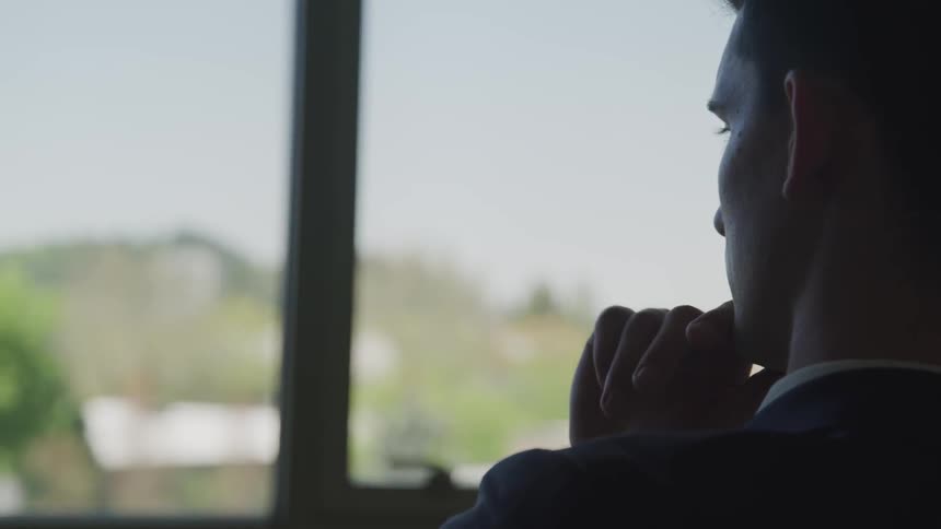A man sits in front of his office window and gazes outside