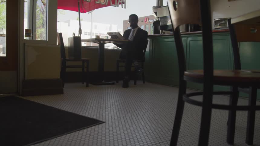 A man sits in a cafe and reads thenewspaper