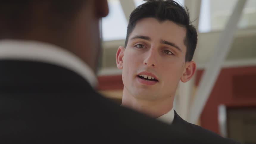 Two men in suits talking to each other indoors