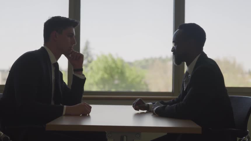 Black and white businessmen sitting at the table have a business conversation in the cafe