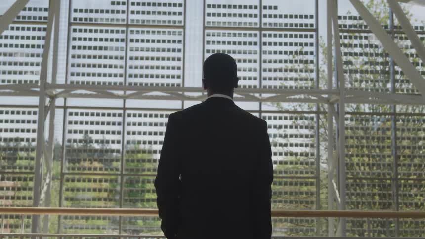 Man stand at balcony rail looking through abstract decorative structure