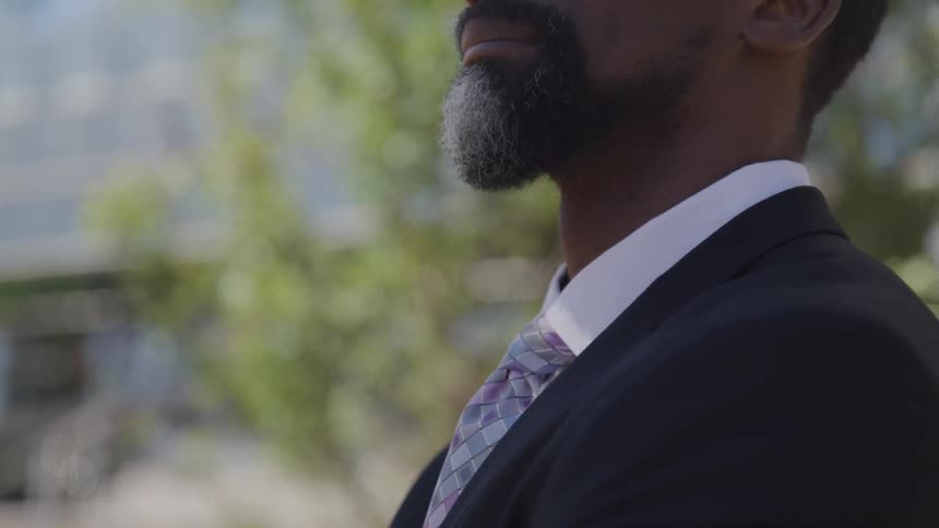 The wind blows tree branches behind a man in a suit