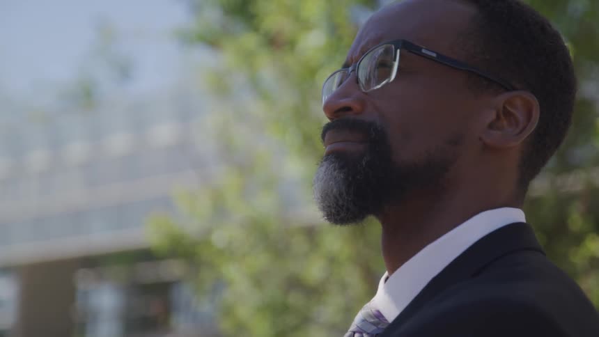 A black man in a suit looks off in to the distance