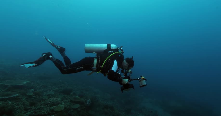 A man scuba diving and taking pictures
