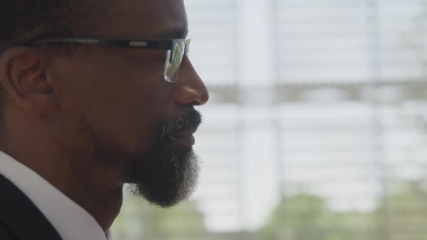 A man wearing eyeglasses nods as he listens