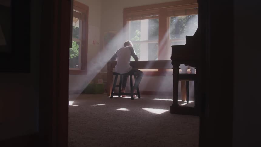 A person sitting down by a desk next to a window