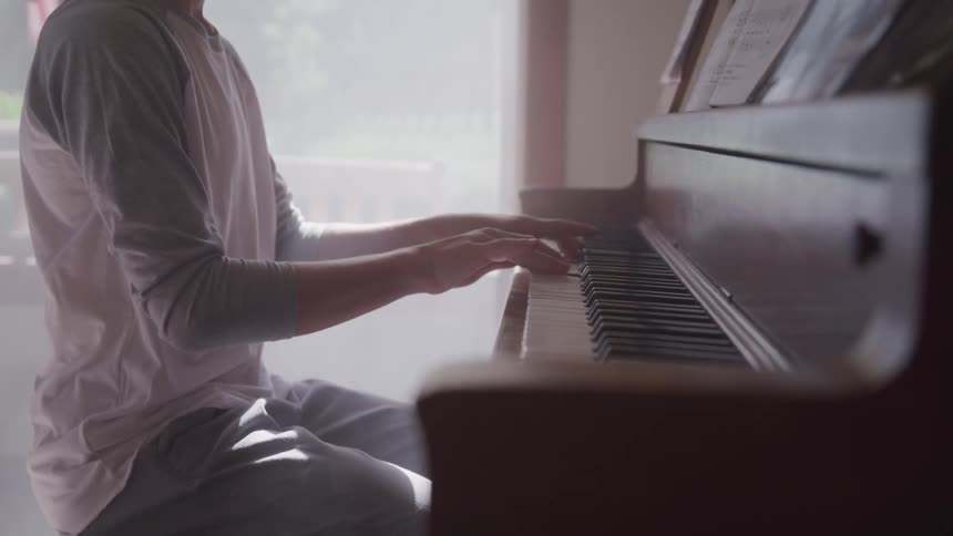 Boy plays the piano while the sun streams through the window