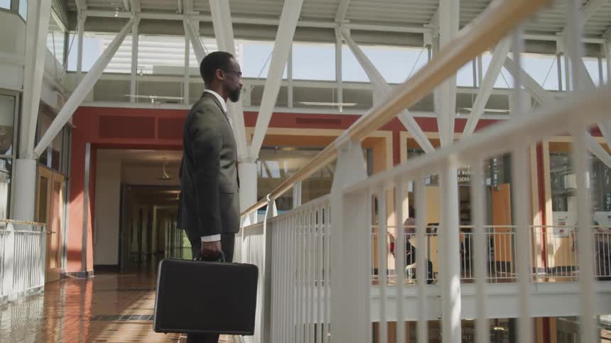 A man stands next to a banister in an atrium and looks down below