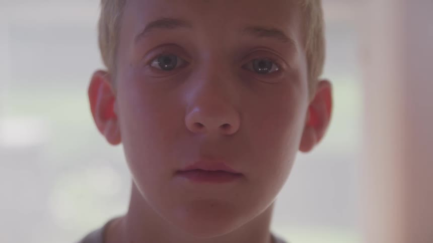 Boy stands staring in room