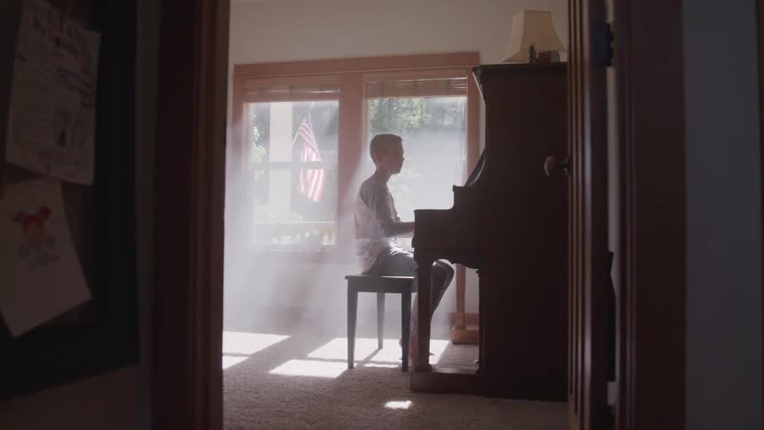 A young boy plays the piano