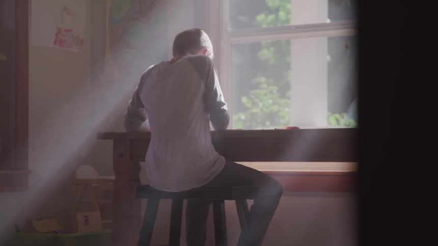 A child is in a room sitting at a desk