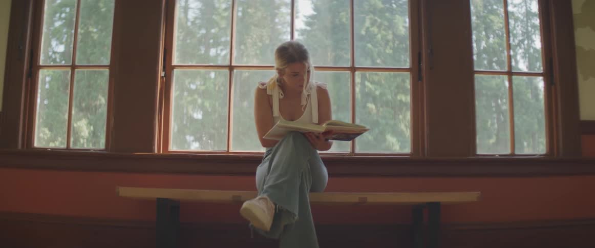 A woman is flipping through a book by the window
