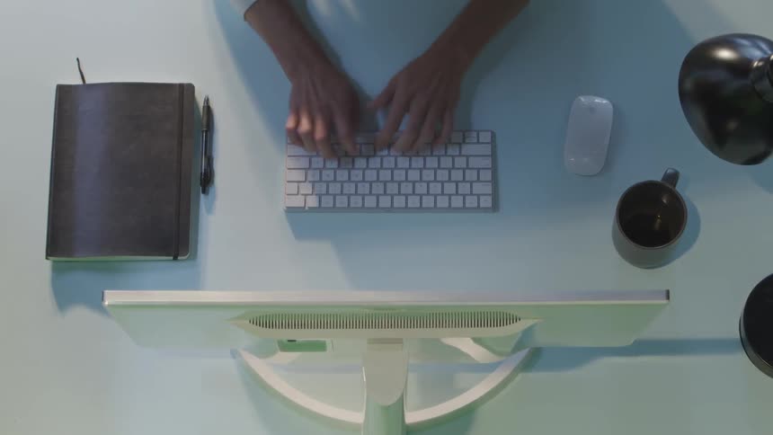 Man sitting at the desk types on the keyboard drinks coffee in a room