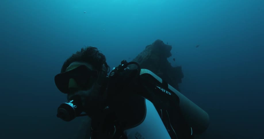 A scuba diver is operating a camera underwater