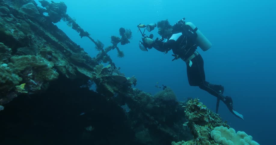 A man is taking photos as he scuba dives underwater