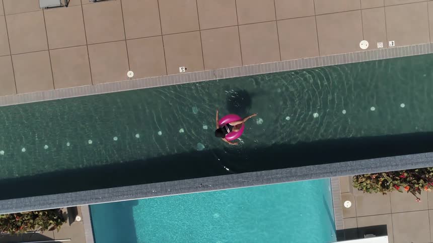 A woman relaxes while floating on an inflatable ring in an infinity pool