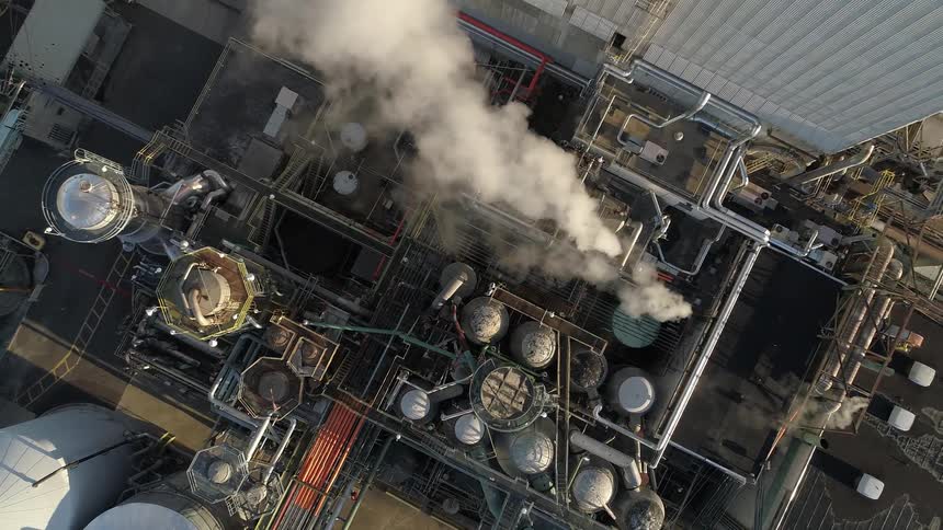 Steam and smoke rises from the stacks and rooftop of the factory and processing plant
