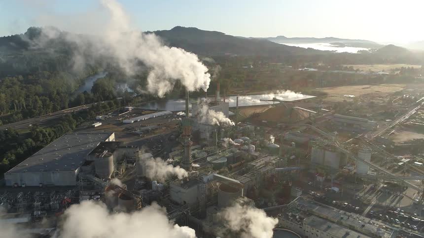 Smoke billowing from an industrial complex near a freeway in the countryside