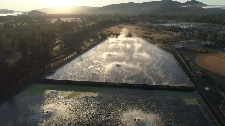 In a rural area two large manmade water collection ponds have steam rising from the surface