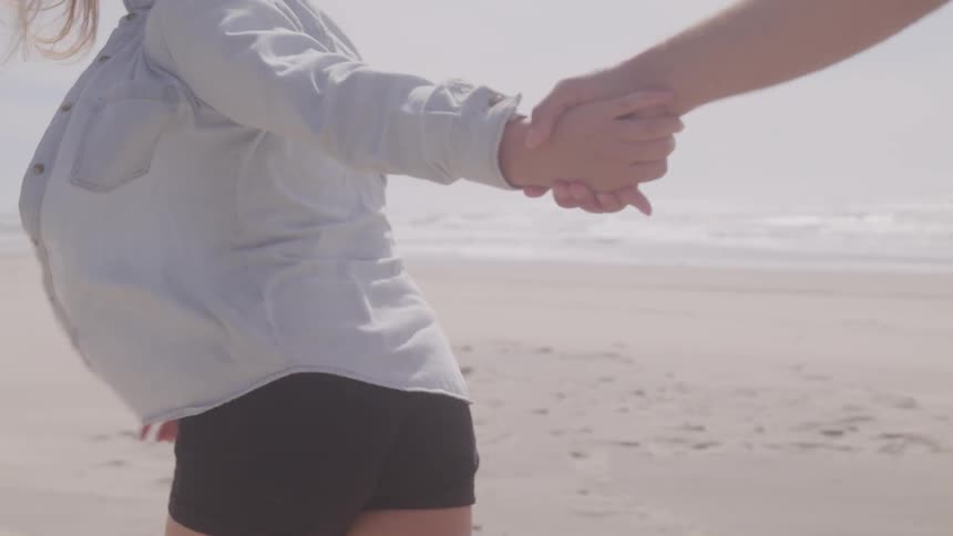 Couple running on the beach while holding hands