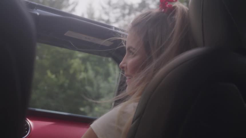 Girl sitting on the side seat looks at the boy driving the car