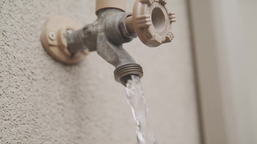 Water flows our of a faucet on the side of a building