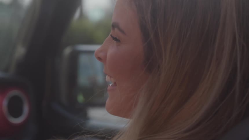 A female sits in a vehicle and laughs