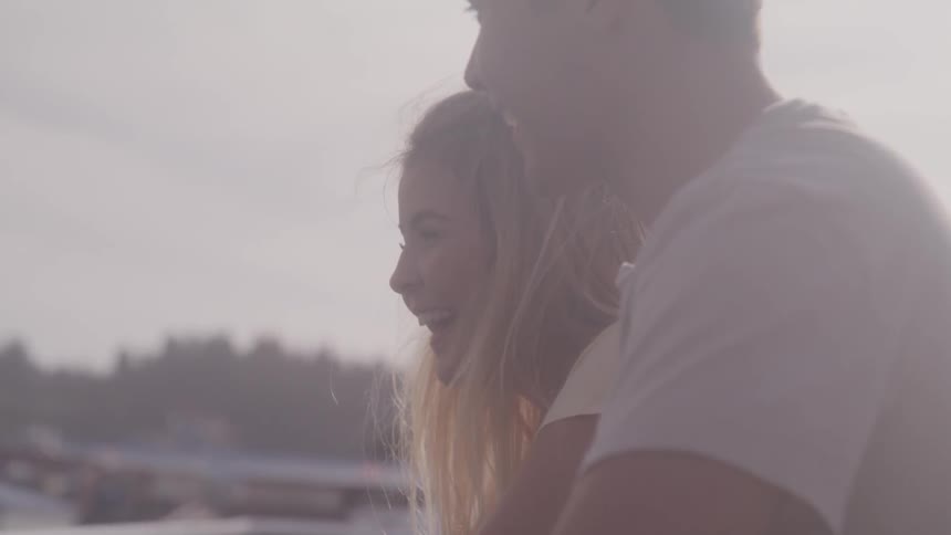 A couple sits together and laughs outdoors