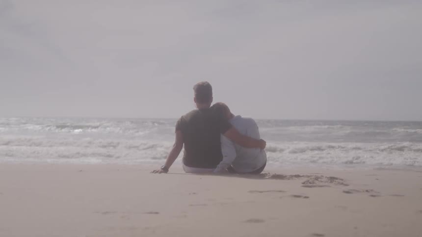 A couple sit on the beach together