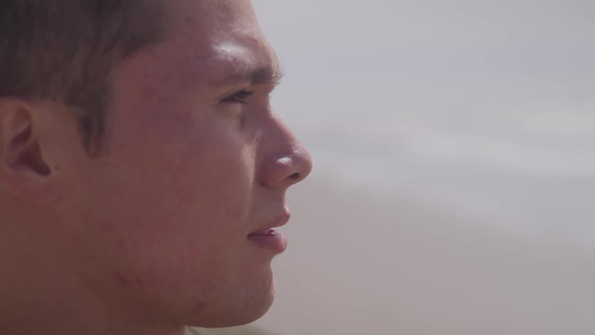 A side profile of a man staring out at something in the light of day