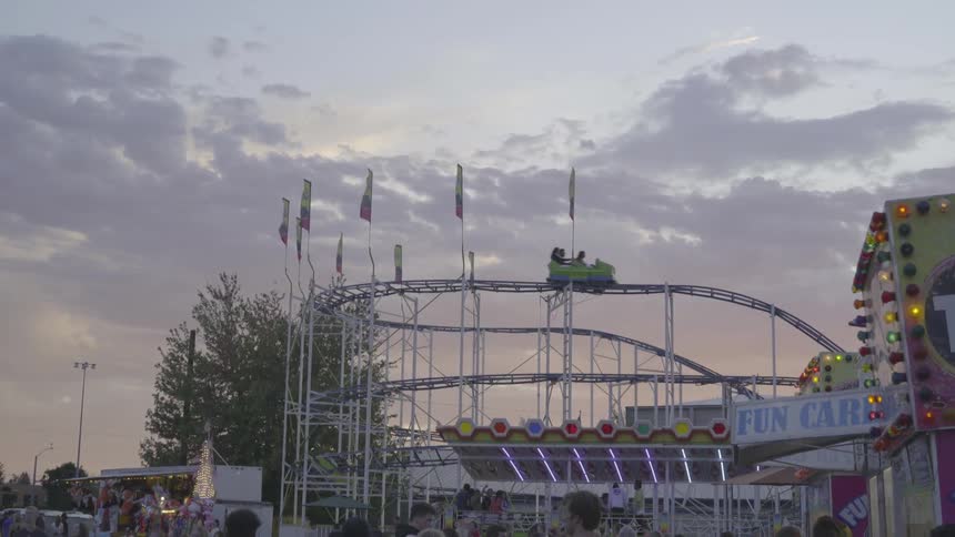 People attend an amusement park featuring a roller coaster