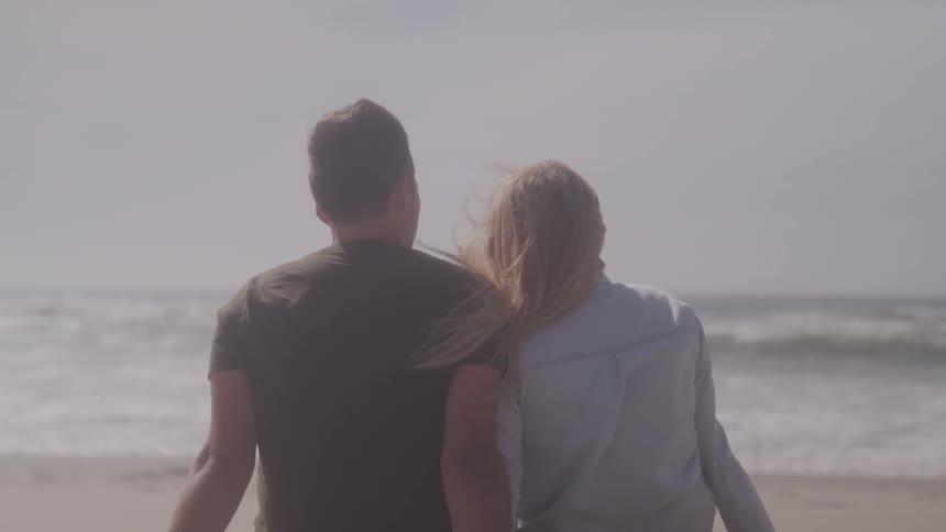 A girl and boy sit on the beach together