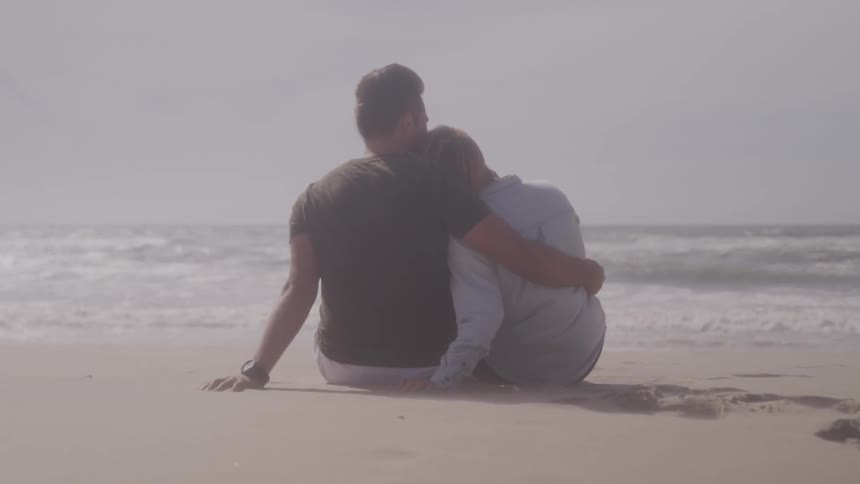 A couple cuddle on a beach